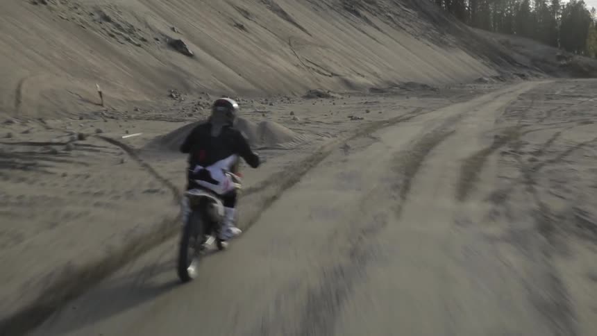 A motorbike moves fast down a dirt track