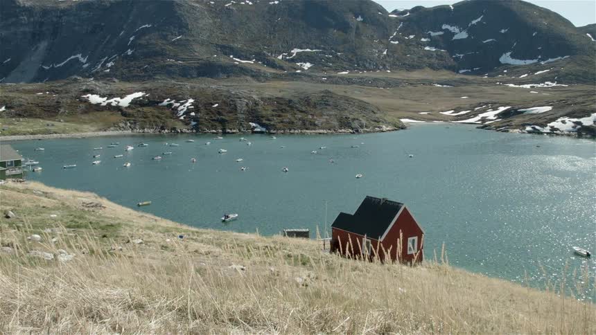 A small red house sits by a lake