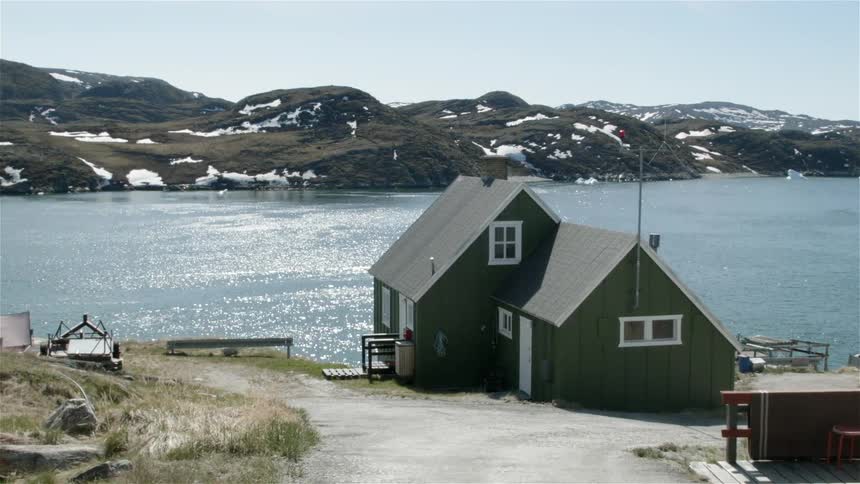 A green house sits on the edge of the pier