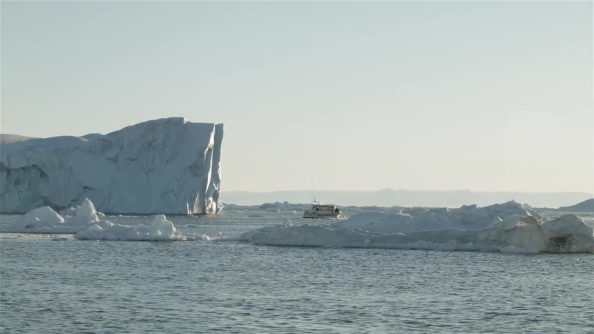 View of a boat in flowing water next to glaciers