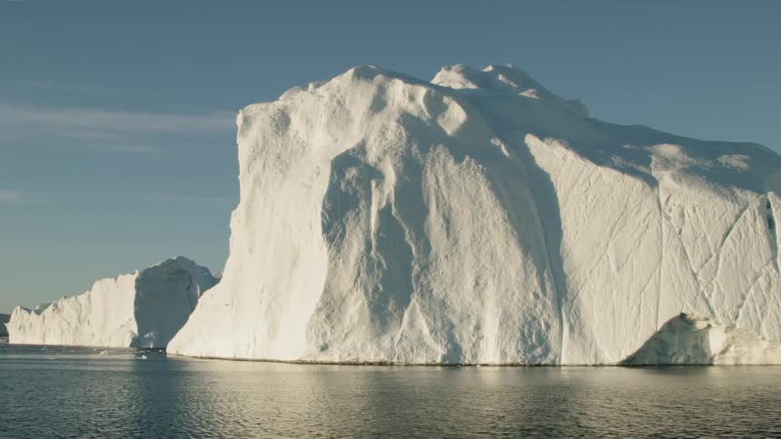 A large iceberg sits in the water on a sunny day