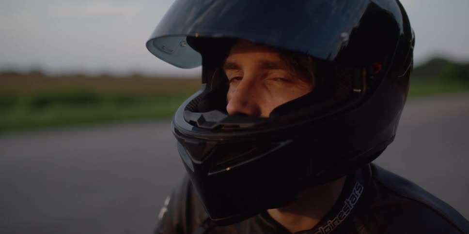 Man wearing a crash standing on a rural road looks at the camera at sunset