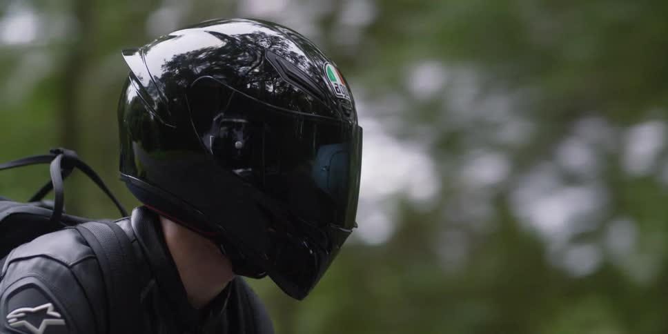Person wearing a black crash helmet riding a bike on near the forest