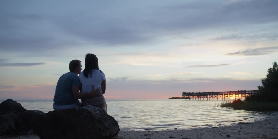 A boyfriend and girlfriend are sitting outdoors