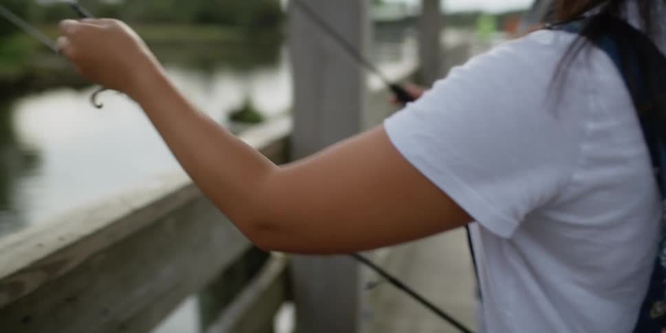 A man and woman fishing off of the pier