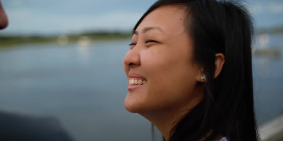 Young couple standing near a lake laugh while talking to each other