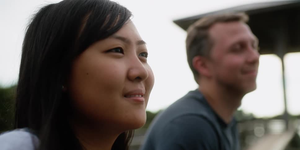 Man looks and smiles at woman with straight hair outdoors