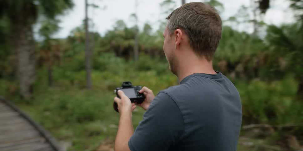 A man is taking pictures of a woman in a tropical area
