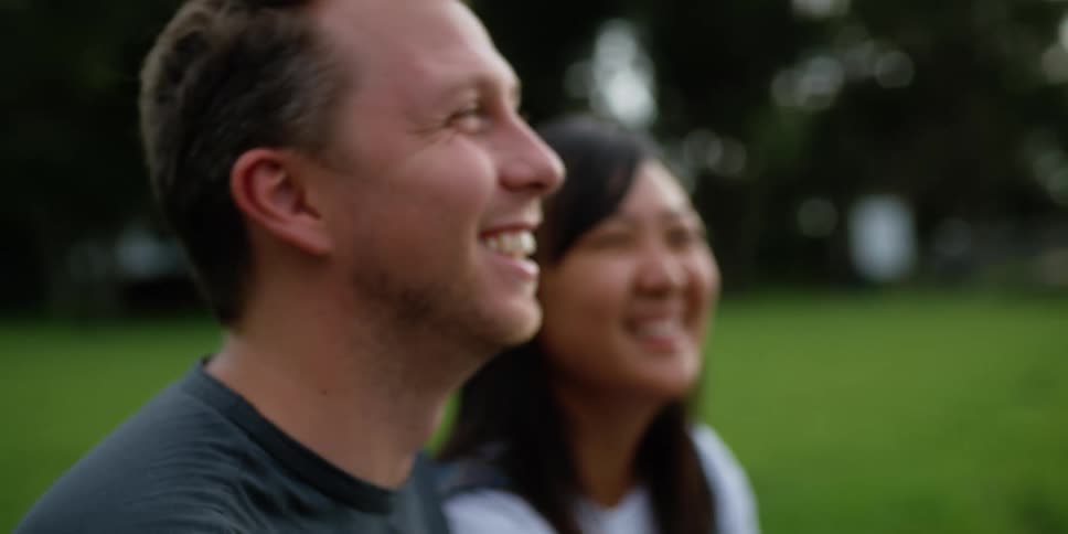 A man and woman laugh in the park