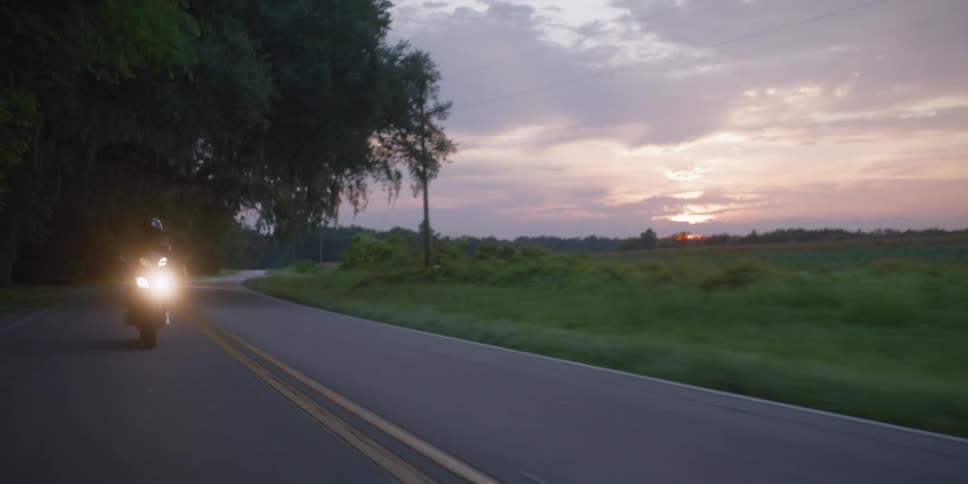 A person is riding a motorcycle on a street at dusk