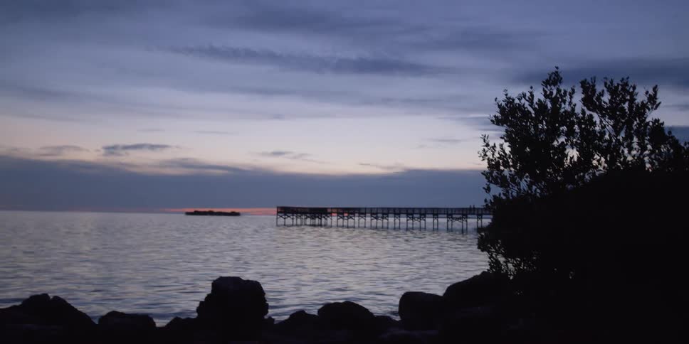 The sun is setting by the shore