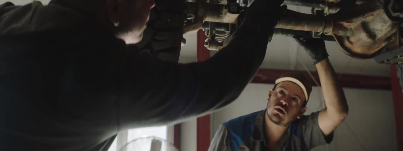 Two mechanics look over a vehicle on the lift