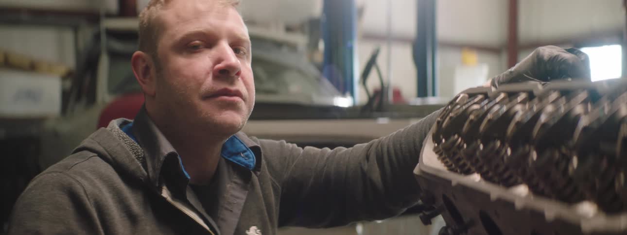 A man is working in an automotive shop during the day