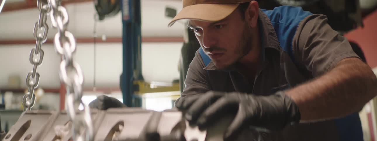 A mechanic leans forward concentrating and working on a vehicle