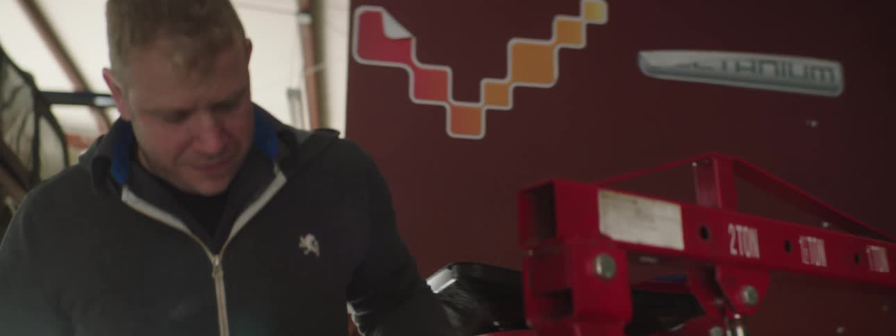 A man moves around a machine equipment in what seems to be a garage