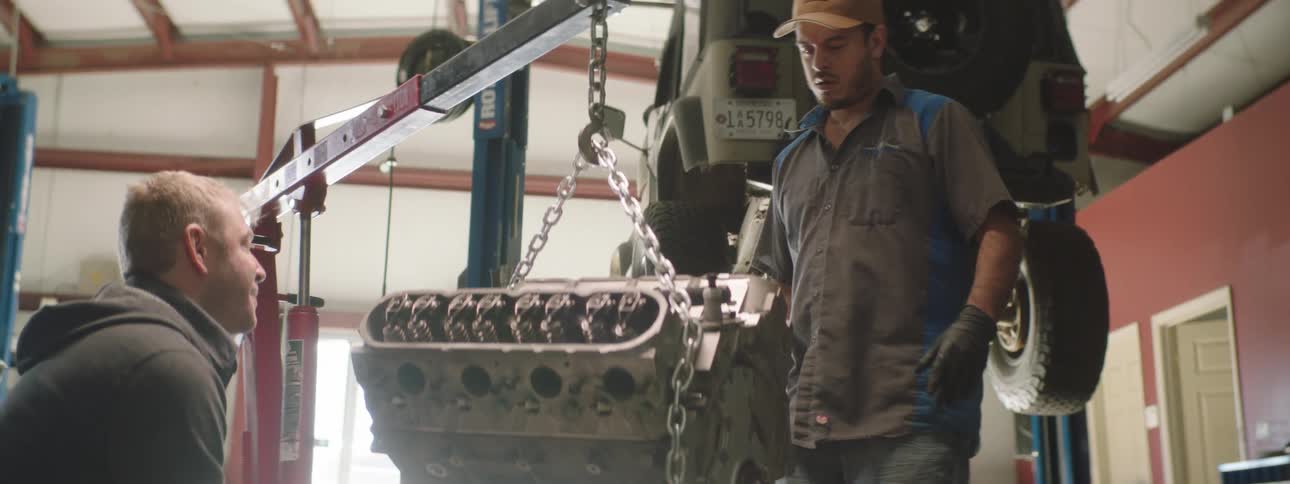 Two men are in a car shop together and talking