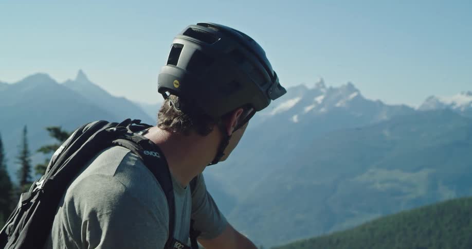 Man with a bike helmet looking at the distant mountain range