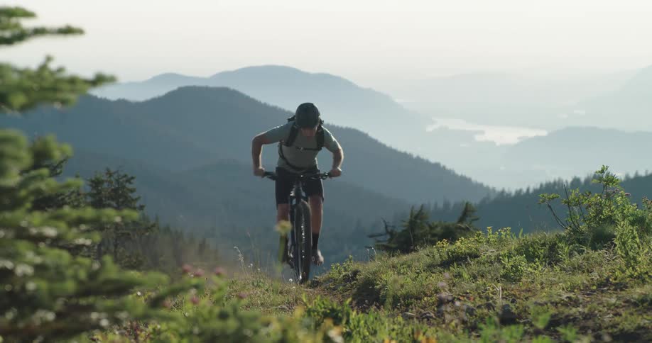A man climbs a steep mountain bike trail out of the valley in the afternoon