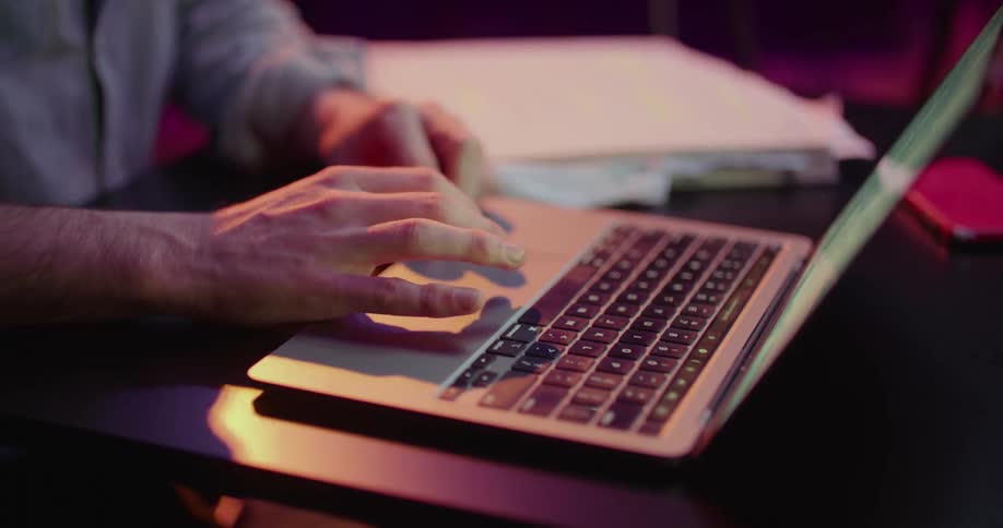 A man that is typing on a laptop in a room