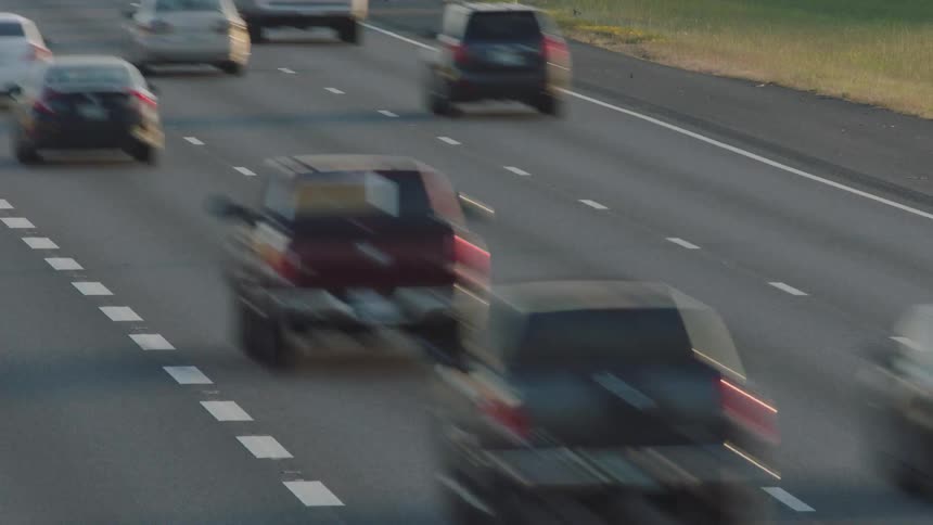 A busy roadway is filled with numerous vehicles that are speeding along it