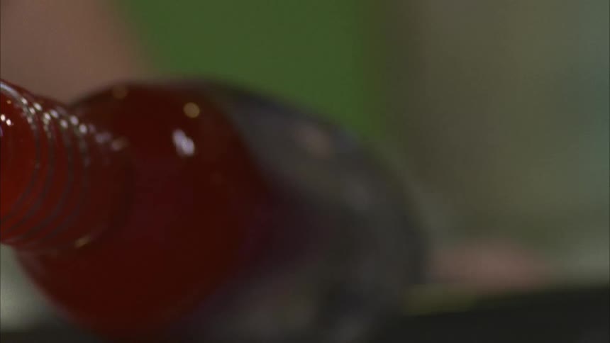 A person rolling a red glass bottle