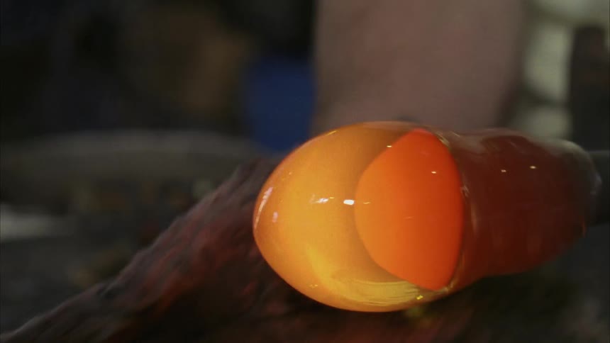 Person making a glass object using heat and spinning