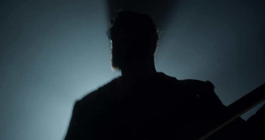 A bright spotlight outlines the silhouette of an energetic guitarist who is jamming on his guitar