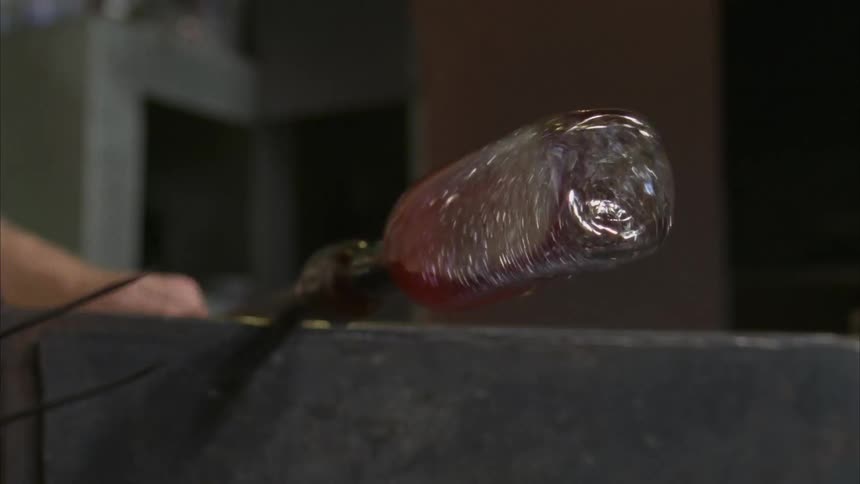 A man molds a glass bottle