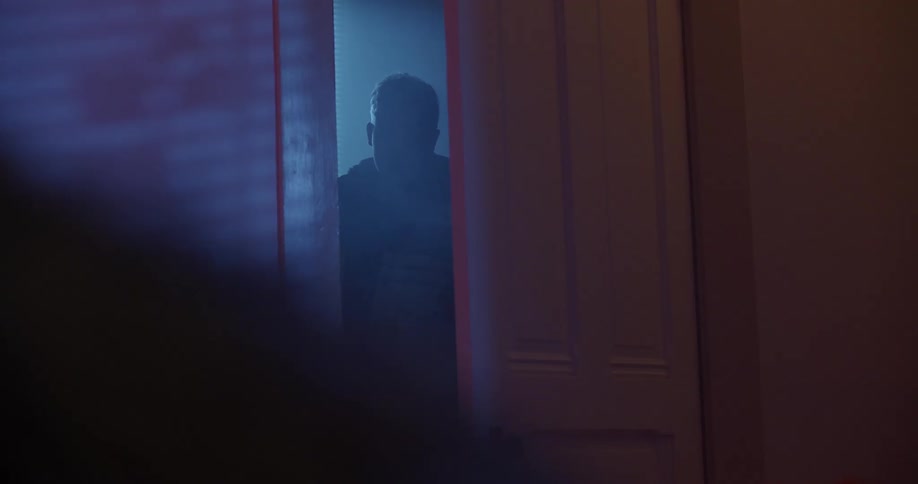 Man stands starting from partly opened door as womans silhouette moves across room