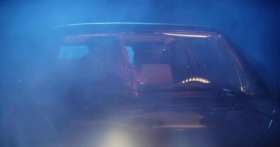 Woman looks fearful inside a car as she reaches to lock the doors