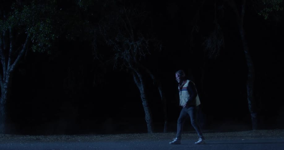 A limping man is being followed by a man wearing all black
