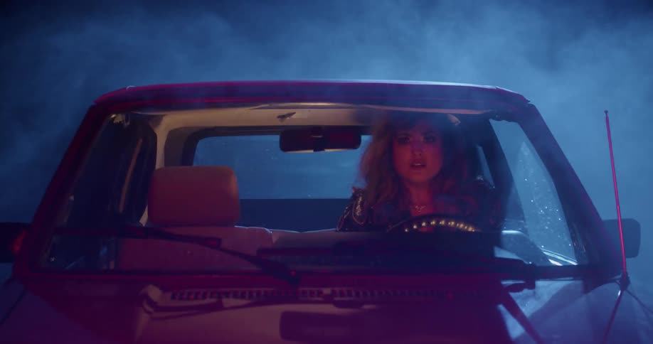 A woman sitting in a vehicle surrounded by smoke