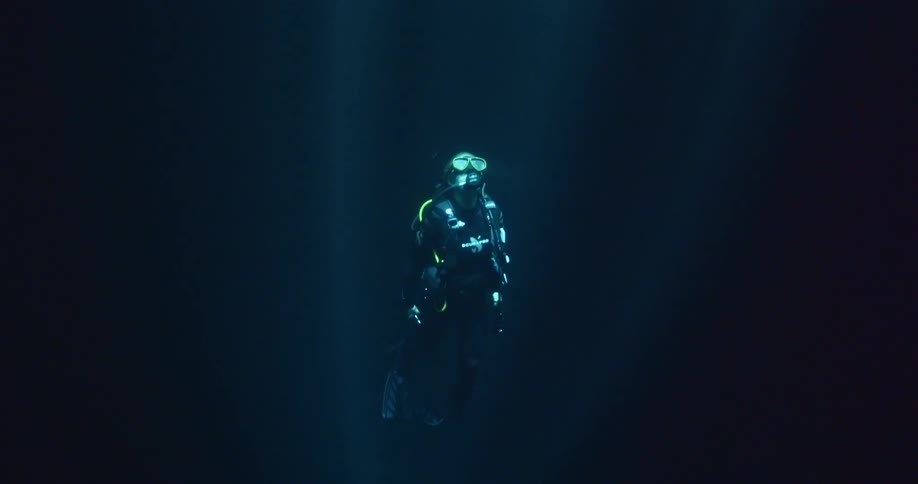 A scuba diver is traveling towards the surface of the water