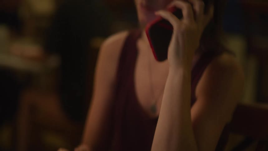 A woman scrolling on a laptop and answering a smartphone