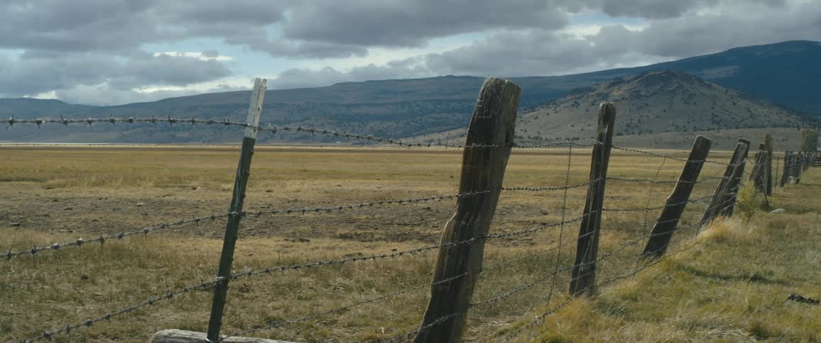 A barbwire fence on a ranch with the wind blowing
