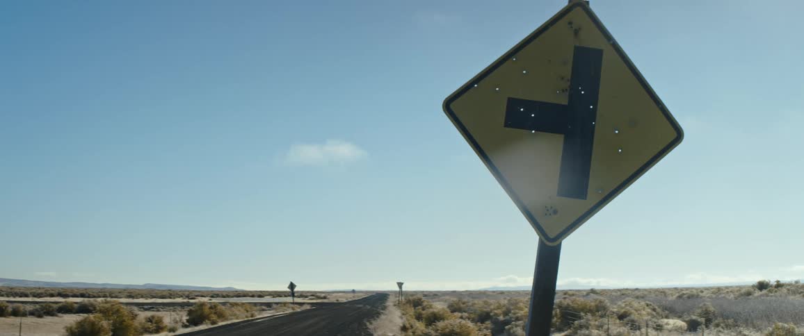 Holes in a highway sign under a blue sky