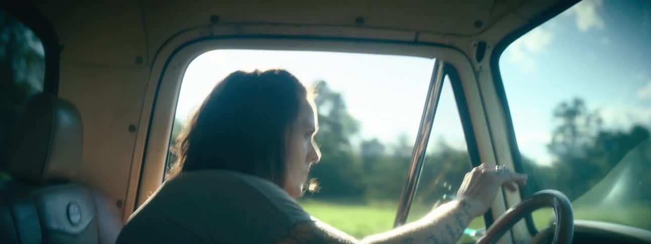 Woman driving a pickup truck over rough terrain in the countryside at morning