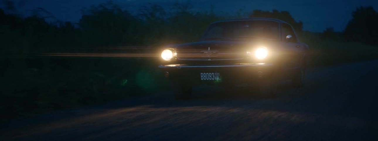 An antique car traveling on a road at night