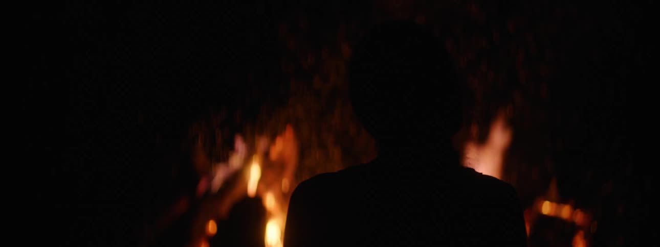 Woman watches a fire burning in the dark