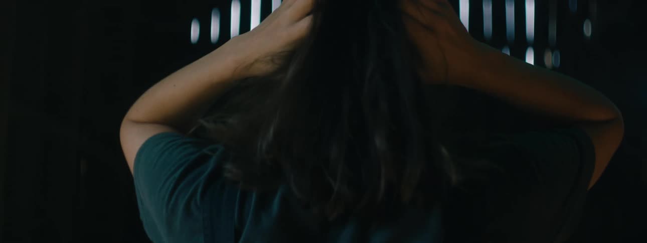 A woman runs her hands through her hair while walking through a barn