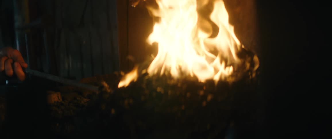 A woman is stirring the burning coals