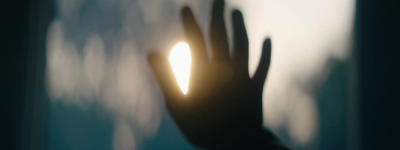 A silhouetted hand backlit by a bright light