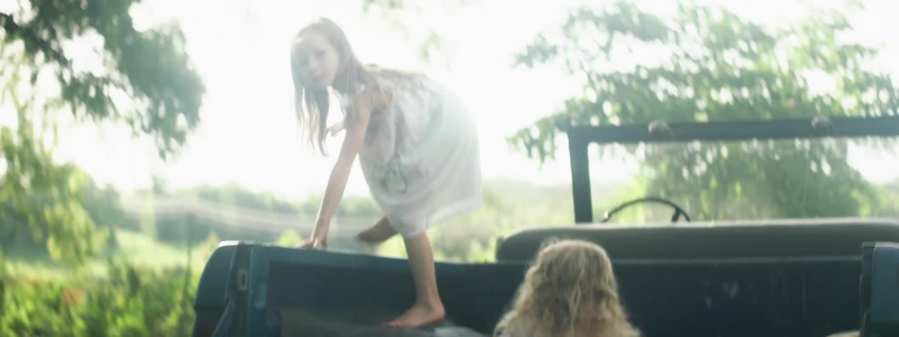 Two little girls playing around in the back of a car that is parked