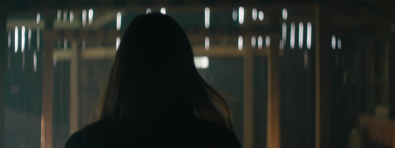 A woman walks briskly through a mostly empty barn towards its door
