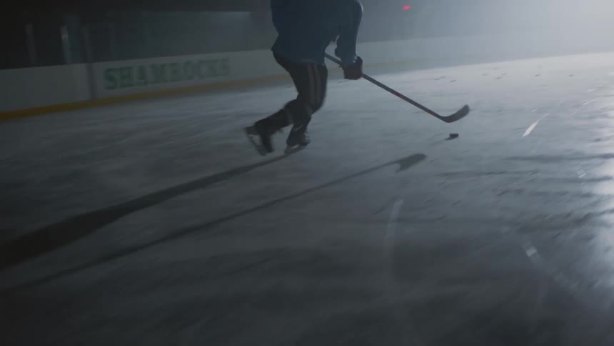 A hockey player is moving pucks on an ice rink