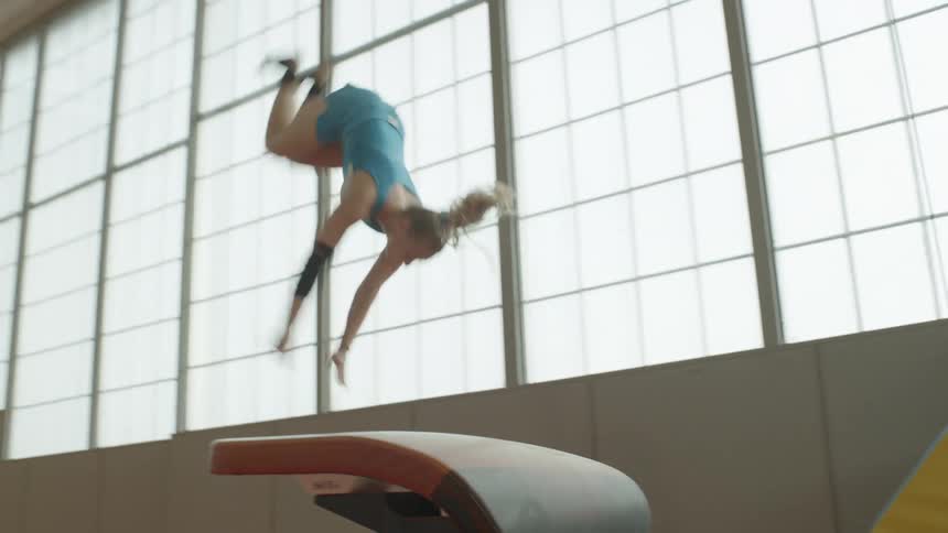 A woman is doing gymnastics in a large gym