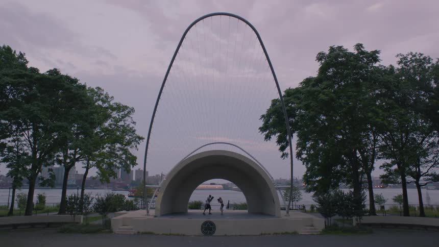 Two people spar under a large city structure