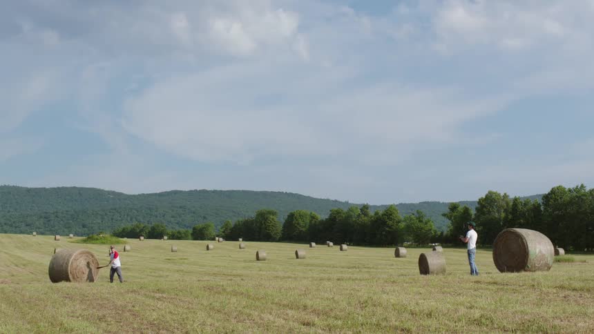 Two people playing baseball in a hay field