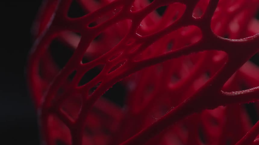 Light moving over sculpture of reddish branches casts shadows before turning off to leave shape in darkness