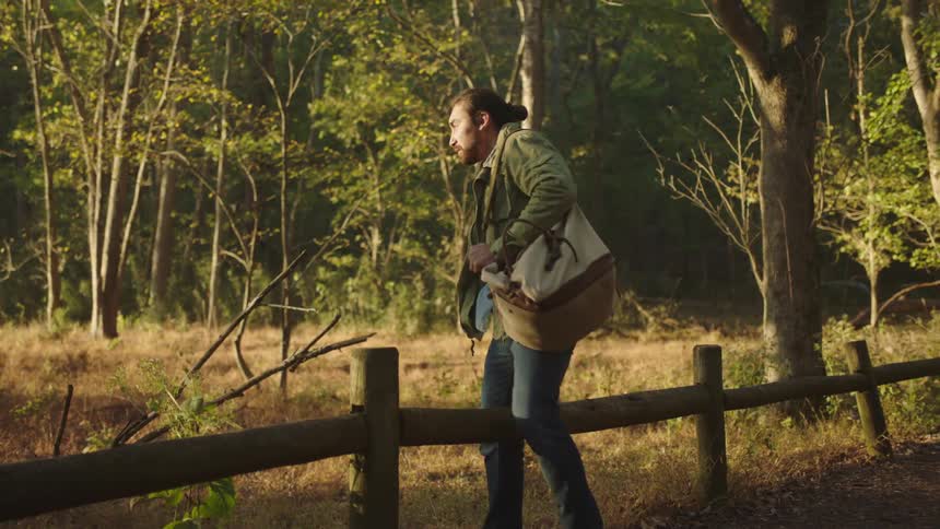 A man sits on the fence and opens his bag